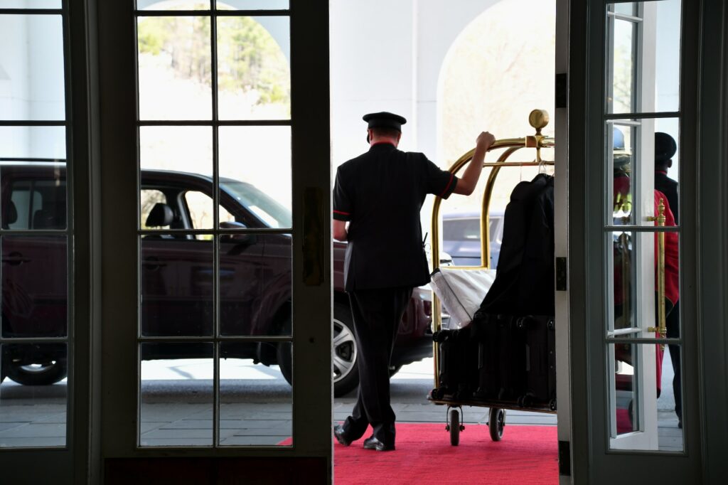 A doorman waiting with a luggage rack while waiting for valet parking at a luxury hotel